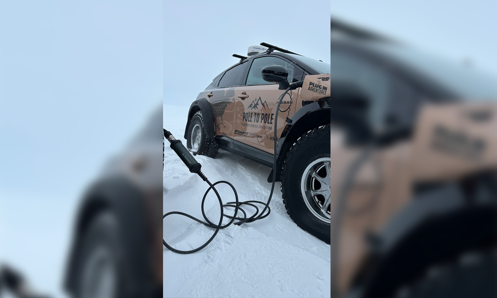 Nissan Expedition Ariya parked in a snowy landscape, plugged into an electric vehicle charger.